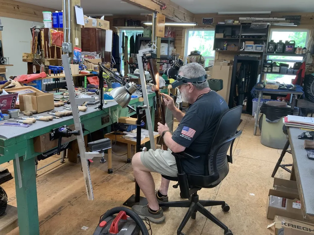 David seated at his bench, working on a stock held upright in a vise