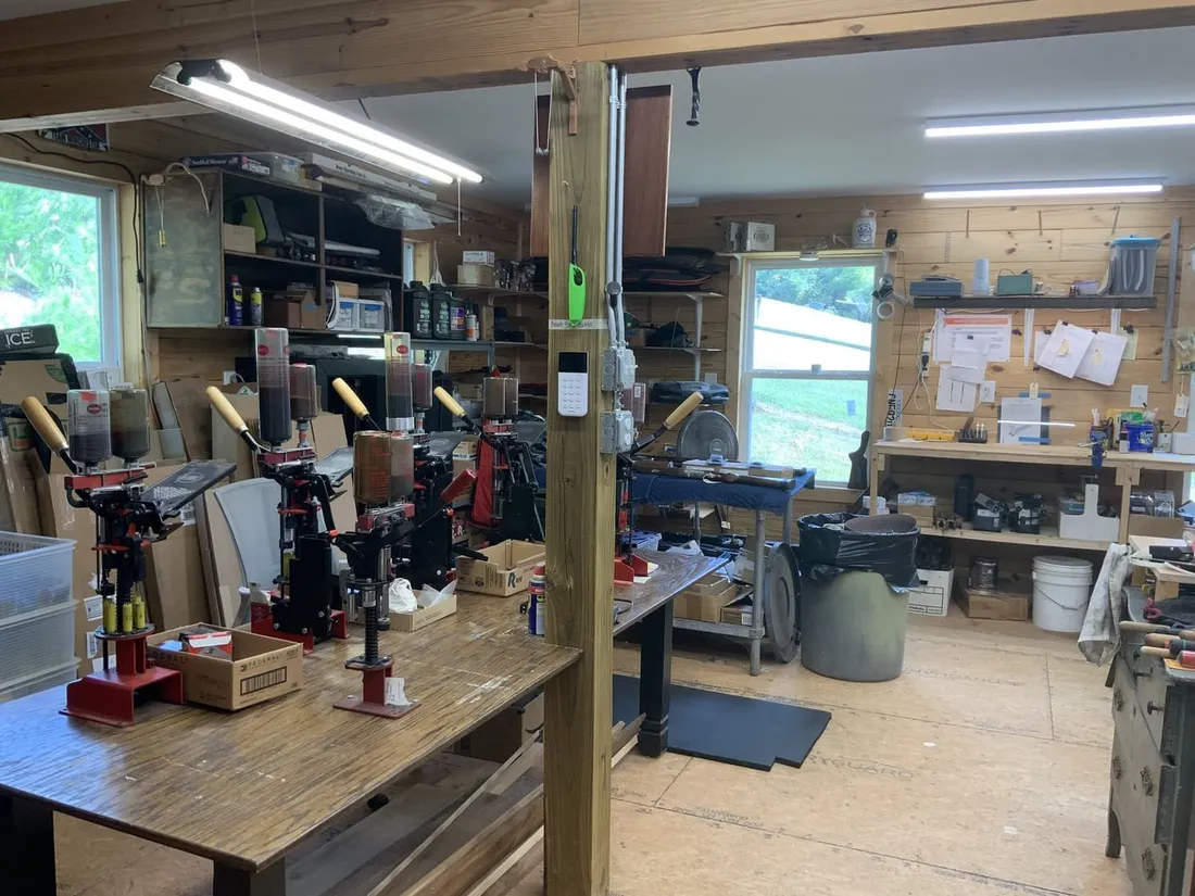The main shop: work benches, a reloading press and daylight from the windows