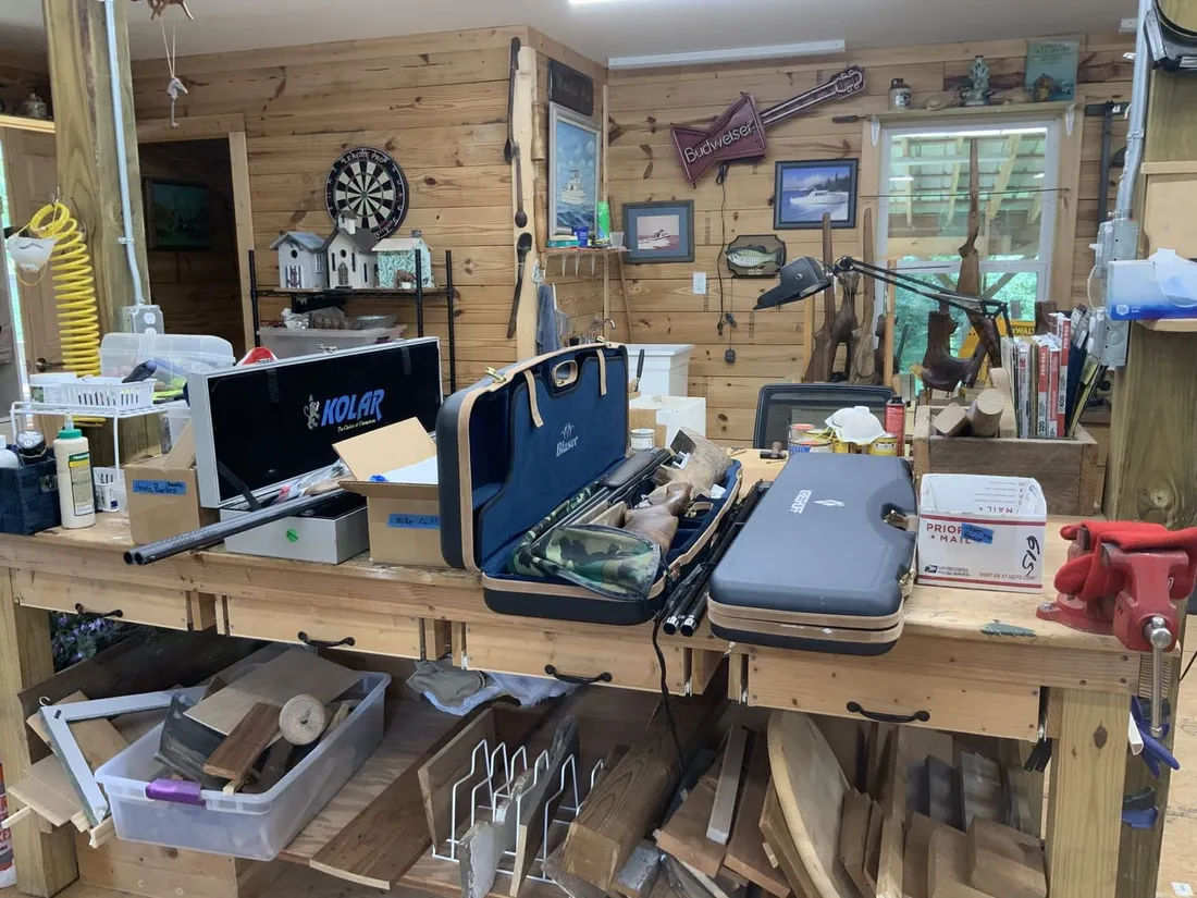 Shop wall hung with tools, with gun sleeves and cases stacked below